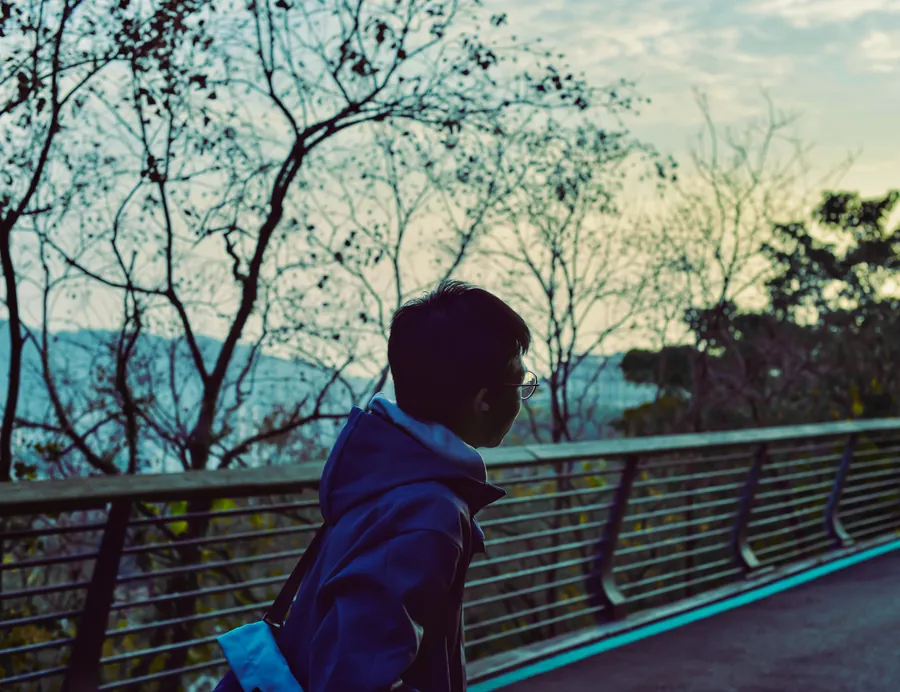 Xincheng Huang outdoors, wearing glasses and a backpack